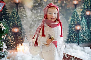 Littlw toddler child with suitcase and little gingerman toy in hand, walking in a snowy forest, christmas picture