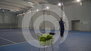 Live camera, sportswoman taking yellow tennis ball and serving it. Wide shot of gym indoor big tennis court with two