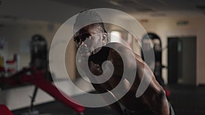 Live camera zoom in to exhausted satisfied African American man resting after workout in gym. Portrait of perspiring