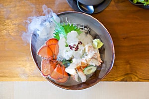 Live Canadian Lobster sashimi on brown ceramic plate with a smoke of dry ice. Served two ways fresh and boiled decorate with fresh