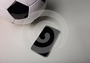 Live football betting concept, blank smartphone screen and classic soccer ball isolated on grey table minimalist background.