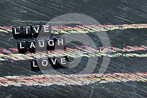 Live Laugh Love on wooden blocks. Cross processed image with blackboard background.