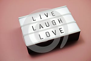 Live Laugh Love word in light box flat lay on pink background