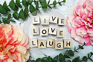 Live Love Laugh alphabet letter with green leave and pink flower flat lay on marble background