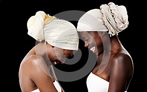Live, love and laugh. Studio shot of two beautiful women wearing headscarves against a black background.