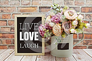 Live Love Laugh text on Blackboard and flower bouquet decoration wooden background