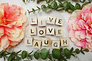 Live Love Laught alphabet letter with green leave and pink flower flat lay on marble background