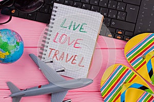 Live Love Travel on notebook with woman`s traveler accessories.