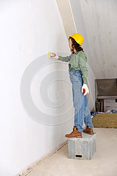 Live portrait of young woman, builder wearing helmet using different work tools at a construction site. Gender equality