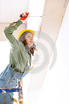 Live portrait of young woman, builder wearing helmet using different work tools at a construction site. Gender equality