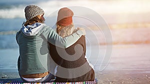 They live the romance. Rearview shot of a young couple sitting on the beach.