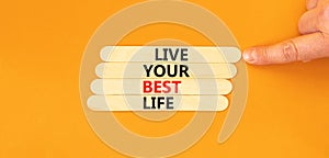 Live your best life symbol. Concept words Live your best life on wooden stick. Beautiful orange table orange background.