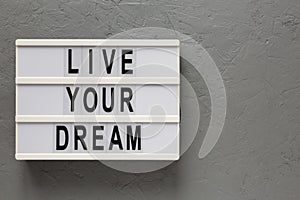 `Live your dream` words on a lightbox on a gray background, top view. Overhead, from above, flat lay. Copy space