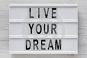 `Live your dream` words on a modern board on a white wooden background, top view. Overhead, from above, flat lay. Close-up