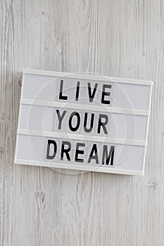 `Live your dream` words on a modern board on a white wooden background, top view. Overhead, from above, flat lay. Close-up