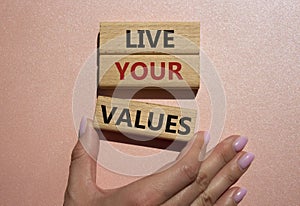 Live your values symbol. Concept words Live your values on wooden blocks. Beautiful pink background. Businessman hand. Busines