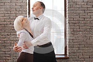 Lively elderly dance couple enjoying tango at the ballroom