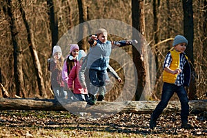 Lively girls and boys, classmates, adventuring on trail, dressed for cold weather with accessories. Outdoor