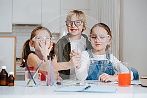 Lively little kids doing home science project, passing a flask