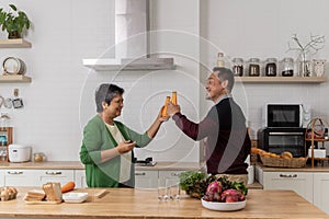 Lively middle-aged family couple dancing to disco music in the kitchen.Happy old man and woman having fun