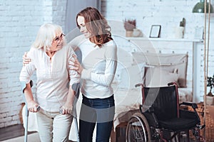 Lively young woman helping disabled aged lady at home