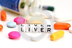 Liver problems concept with close-up of colorful pills and liver word on white background