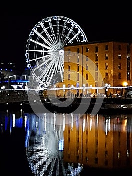 Liverpool docks at night with a big wheel reflected in the river