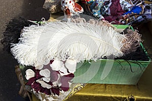 Liverpool Street, London, UK,- 21 September 2020, Spitalfields Antique Market. A large white ostrich feather lies on a box of silk