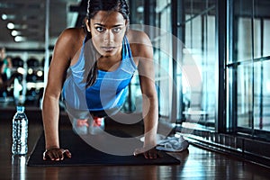She lives strong. an attractive young woman doing pushups as part of her workout in the gym.