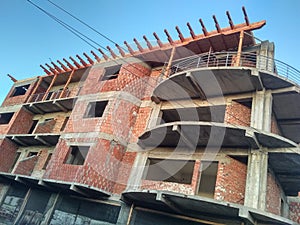 Living block construction site, concrete structure and brick walls, wood element for rooftop and blue sky on the background