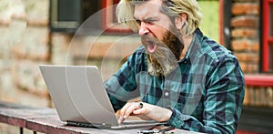 Living in digital age. angry man sitting in cafe with laptop and checking email. Freelancer man working on computer