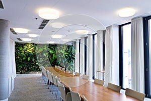 Living green wall, vertical garden indoors with flowers and plants under artificial lighting in meeting boardroom