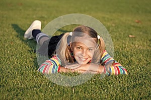 Living happy life. Cheerful schoolgirl on sunny day. Happy smiling pupil. Have fun. Girl kid laying green grass. Healthy
