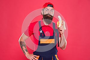 Living healthy life. Tasty and yummy concept. Bite banana. Handyman hungry. Have healthy snack. Bearded man in uniform