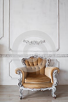 Living room with antique stylish beige armchair on luxury white wall design bas-relief stucco mouldings roccoco elements