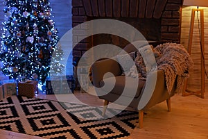 Living room with armchair and fireplace decorated for Xmas. Xmas room interior design, Christmas tree decorated with lights and ga