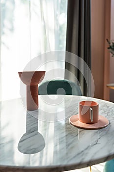 Living room corner decorated with clay ceramic vase and baby pink cup on white marble  table with pink tile stair in the