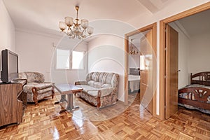 Living room with doors to other rooms and checkerboard parquet floor and three-seater sofa upholstered in fabric with wooden