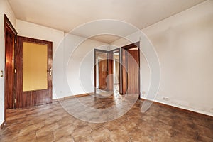 Living room of an empty apartment with cheap dark wood carpentry and brown tile floors photo