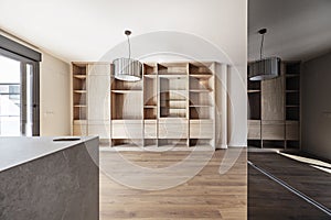 Living room of an empty house with custom built oak bookcase open plan kitchen with island and white goods with black glass panels