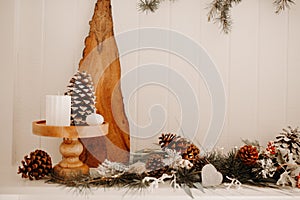 Living room and fire place winter holidays decoration - pine cones and Christmas tree branches garland with string lights and snow