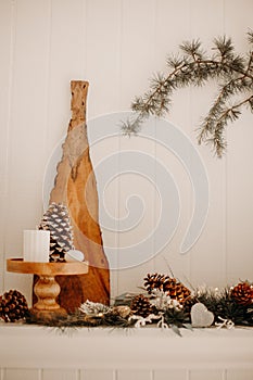 Living room and fire place winter holidays decoration - pine cones and Christmas tree branches garland with string lights and snow