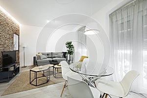 Living room with gray sofa, tv, circular glass dining table, white curtains