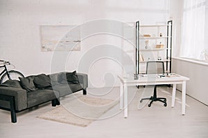 Living room with grey sofa, white table and rack with books