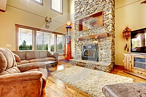 Living room with high ceiling, stone fireplace and leather sofa.