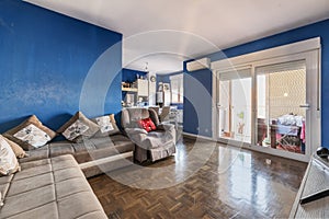 Living room of a house with blue painted walls and a long gray sofa along the wall