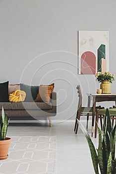 Living and dining room interior with brown sofa and wooden table with vintage chairs