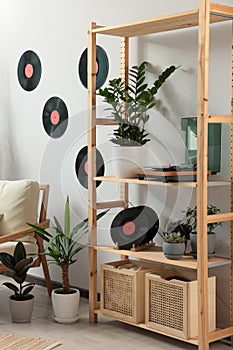 Living room interior with stylish turntable on wooden shelving unit and vinyl records