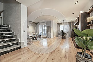 Living room with pine wood floors, marble stairs, dark wood dining table, matching bookshelf and black upholstered chairs