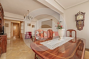 living room with reddish wood dining table with matching glass bookcase, fabric upholstered sofa and oak parquet floors